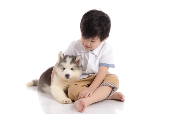 Mignon asiatique garçon assis avec sibérien husky chiot — Photo