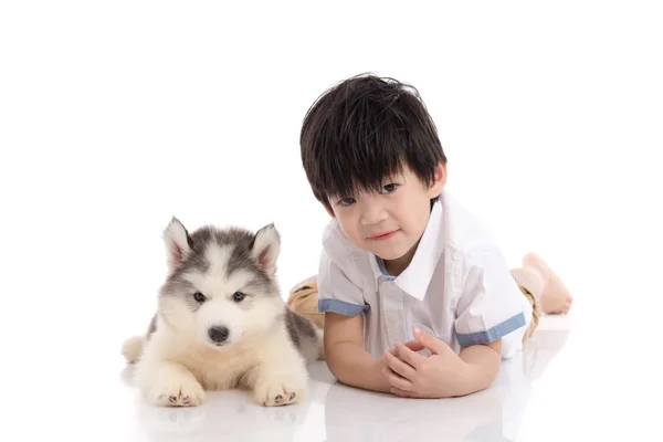 Roztomilé asijské boy a sibiřský husky štěně ležící — Stock fotografie