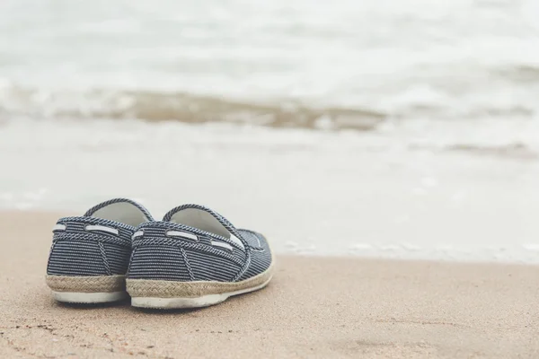 Canvas skor på sandstrand — Stockfoto