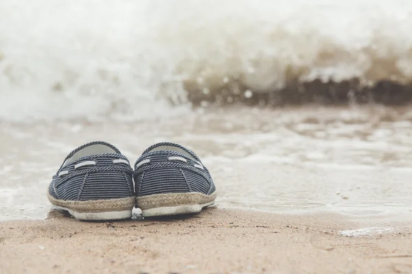 Canvas skor på sandstrand — Stockfoto