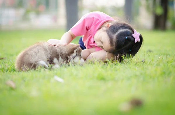 Bella ragazza asiatica che gioca su erba verde con un cucciolo — Foto Stock