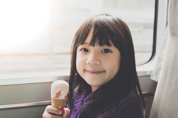 Маленькая азиатская девочка улыбается и ест мороженое — стоковое фото