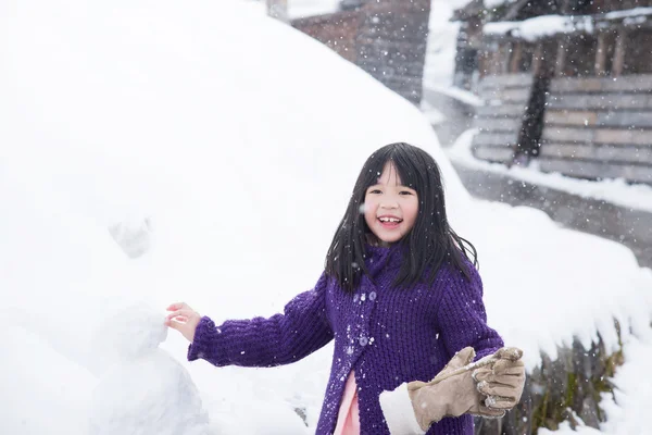 Мила азіатська дівчина посміхається на відкритому повітрі в снігу — стокове фото