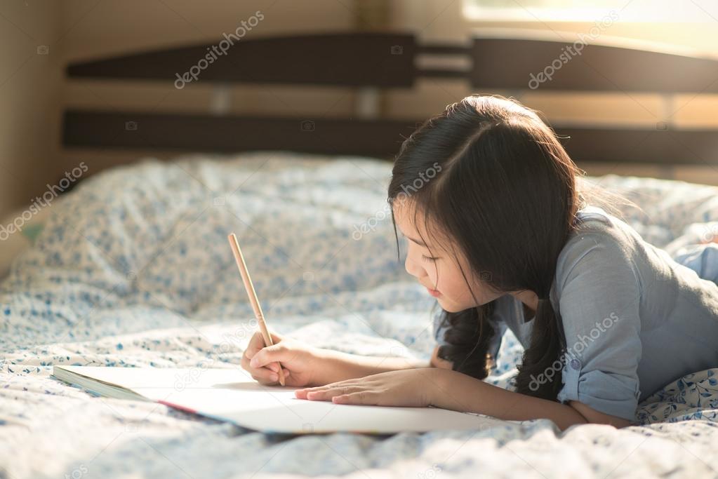 Beautiful asian girl writing to diary