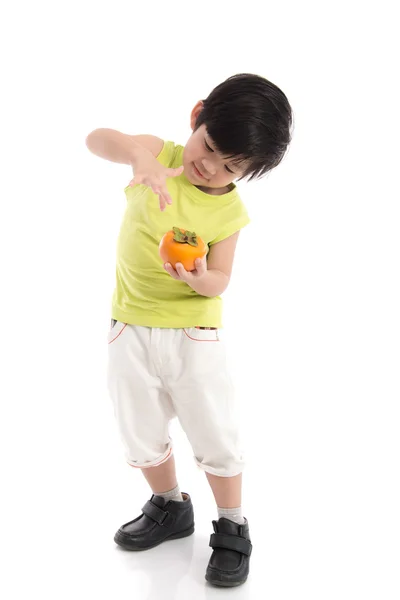 Carino asiatico ragazzo holding cachi — Foto Stock