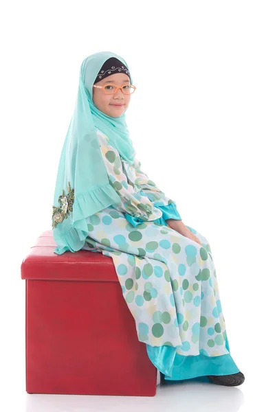 Gadis muslim Asia duduk di bangku merah — Stok Foto