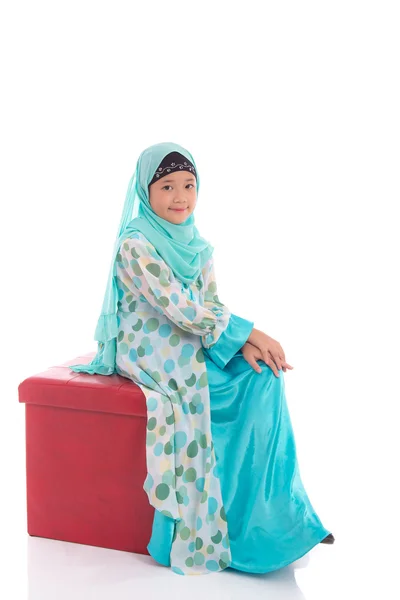 Gadis muslim Asia duduk di bangku merah — Stok Foto