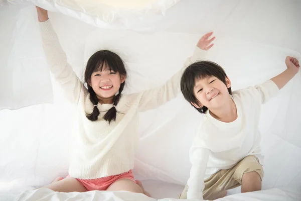 Милые азиатские дети играют на кровати — стоковое фото