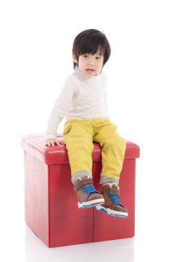 İzole kırmızı taburede oturan sevimli Asya çocuk