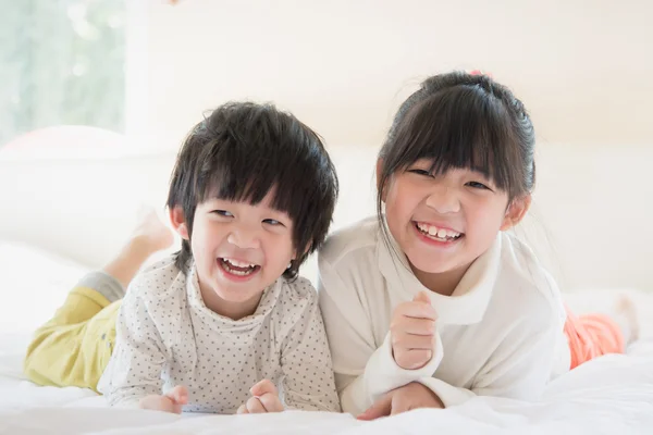 Asian children lying on white bed — Stock Photo, Image