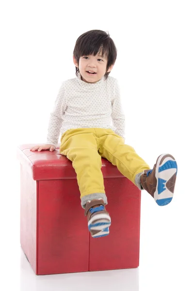 Söta asiatiska pojken sitter på röd pall isolerade — Stockfoto