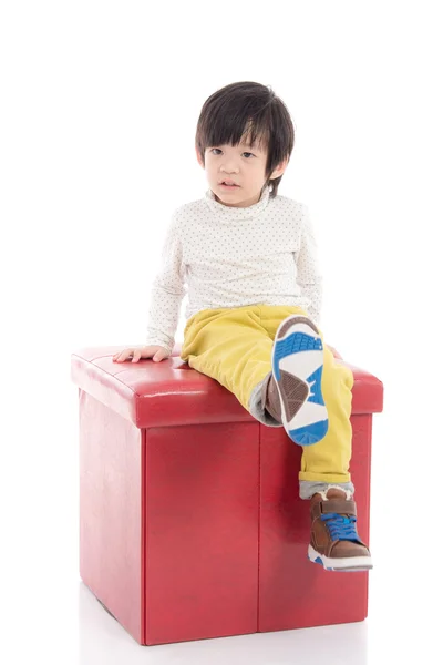 Söta asiatiska pojken sitter på röd pall isolerade — Stockfoto