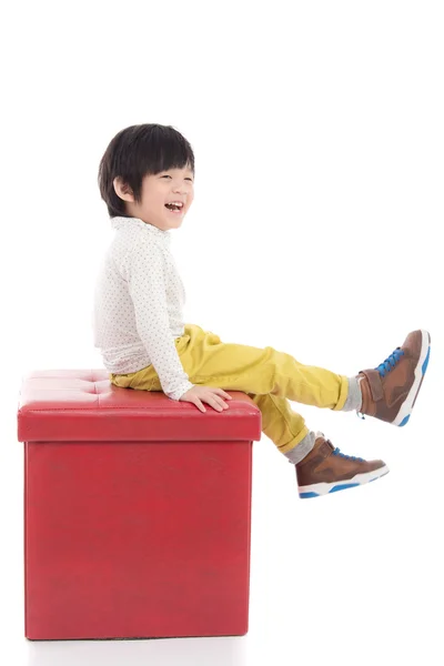 Mignon asiatique garçon assis sur rouge tabouret isolé — Photo