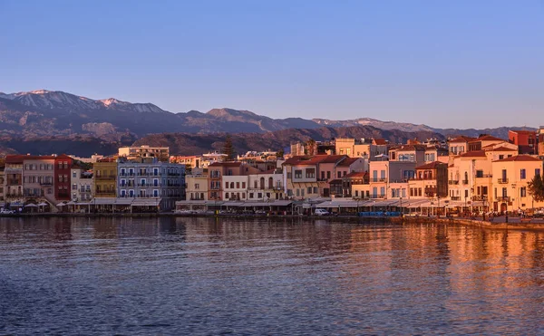 Sunrise at Old Venetian harbour of Chania, Crete, Greece, shop, hotels, cafes and restaurants on its quay in first sunrays. Cretan hills and mountains — Photo