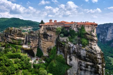 Meteora, Yunanistan 'daki Varlaam manastırının tepesinde kayalık sütunlar ve yamaçlardan oluşan tipik bir Meteora manzarası var. UNESCO Dünya Mirası