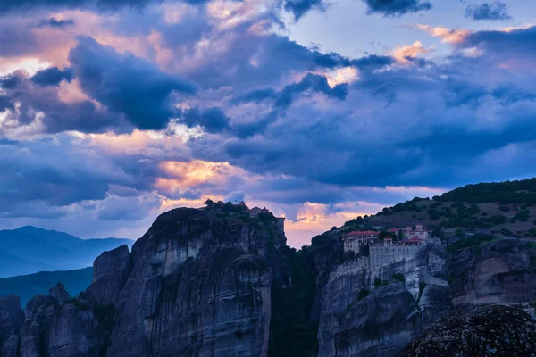 Yunanistan 'ın Meteora kentindeki Varlaam ve Büyük Meteoron manastırları üzerinde alacakaranlık. Bulutlar ve güneş ışınlarıyla gün batımı. UNESCO Dünya Mirası — Stok fotoğraf