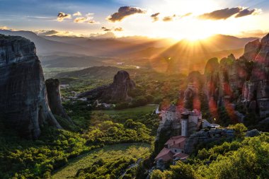 Günbatımında Meteora Vadisi 'nin ikonik manzarası, dağlar, kayalar, Moni Agias Varvaras Roussanou manastırı, doğal lens alevi, Yunanistan, UNESCO Dünya Mirası