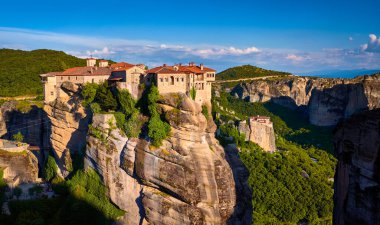 Uçurumun tepesindeki Varlaam manastırı, akşam güneşi, Meteora, Yunanistan, tipik kaya manzarası. Moni Agias Varvaras Roussanou manastırı. UNESCO Dünya Mirası