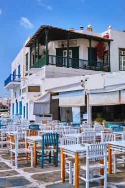 Tipik bir Yunan ada kasabasında açık bir kafe ya da restoran. Kilise, mavi kubbe, turistler dolaşıyor. Güneşli bir yaz günü, Mykonos, Cyclades, Yunanistan. Dikey çekim