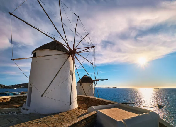 그리스의 미코노스에 있는 유명 한 관광 명소다. 두 개의 전통적으로 회칠을 한 풍차가해 변위에 떠 있는 바 다 앞 과낮은 태양 아래서 부는 풍차. — 스톡 사진