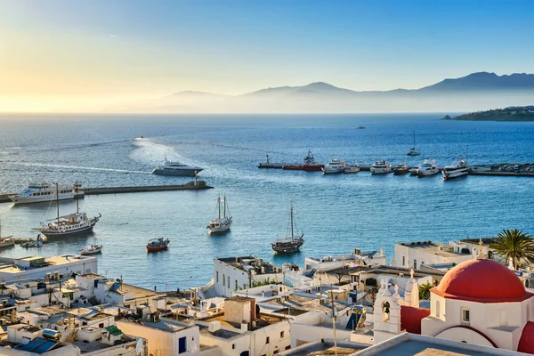 Piękny widok na Chora, Mykonos, Grecja o zachodzie słońca. Port, zatoka, łodzie, jachty zacumowane pomostem. Słynne bielone domy, biały kościół z czerwoną kopułą — Zdjęcie stockowe