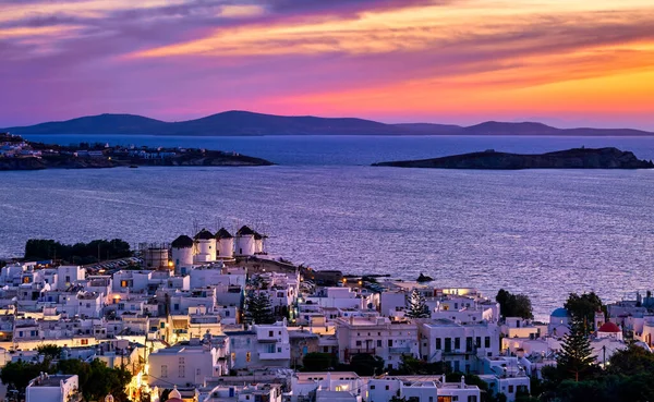 Prachtige zonsondergang uitzicht op beroemde traditionele witte molens op heuveltop, Mykonos, Griekenland. Witgekalkte huizen, zonsondergang hemel, zomer, stadslichten aan — Stockfoto