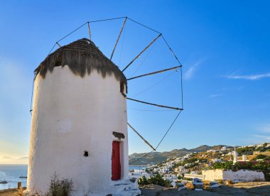 Yunanistan 'ın ünlü Mykonos turistik merkezi. Tepedeki geleneksel yel değirmeni. Yaz, gün batımı, mavi gökyüzü. Seyahat hedefi, ikonik görünüm.