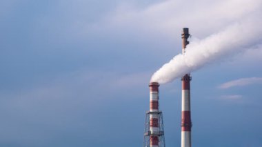 Karanlık mavi gökyüzü ve bulutlara karşı birleşik ısı ve güç istasyonunun 4K zaman kaydına. Rüzgarda sallanan beyaz duman.