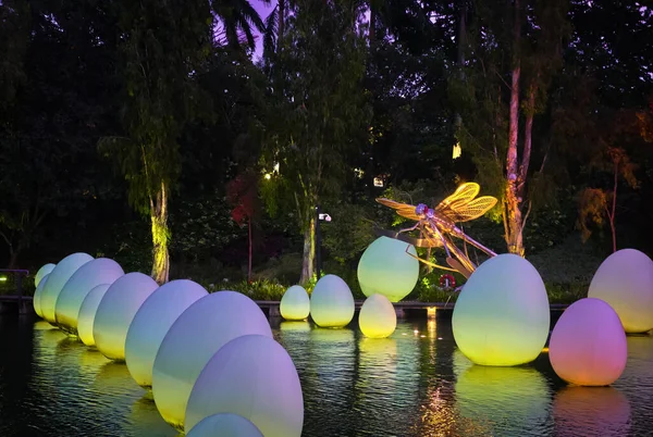 Singapore - Feb 25, 2020. Dragonfly statue over Dragonfly lake in temporary event Future Together, created by Japanese art teamLab. Floating neon eggs — Stock Photo, Image