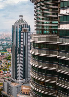 20 Kasım 2019 - Kuala Lumpur, Malezya Petronas İkiz Kuleleri 'nin simgesel paslanmaz çelik cephesinin ayrıntıları, Menara Halk Bankası kulesi görünür. Şehir merkezindeki iş bölgesi, şehir binaları, cam desenler, parlak gün ışığı, şehir manzarası.. 