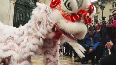 9 Şubat 2024 - Lizbon, Portekiz: Güneşli bir günde düzenlenen Ay Yeni Yılı kutlamaları sırasında Avrupa açıkhava meydanında dans ettikten sonra geleneksel Çin Kırmızı ve Beyaz Aslanları ile fotoğraf çektirmek için poz veren seyirci. Aslan dansı şans, servet ve refah getirir.