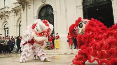 9 Şubat 2024 - Lizbon, Portekiz: Güneşli bir günde düzenlenen Ay Yeni Yılı kutlamaları sırasında Avrupa açıkhava meydanında dans ettikten sonra geleneksel Çin Kırmızı ve Beyaz Aslanları ile fotoğraf çektirmek için poz veren seyirci. Aslan dansı şans, servet ve refah getirir.