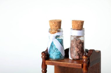 Ahşap raftaki iki şişe banyo kristali beyaz arka planda izole bir şekilde duruyor. Resim kopyalama alanı içeriyor