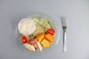 Dükkan teslimatı konsepti, salata malzemeleri kaseleri ve gri arka planda bir çatal. Resim kopyalama alanı içeriyor