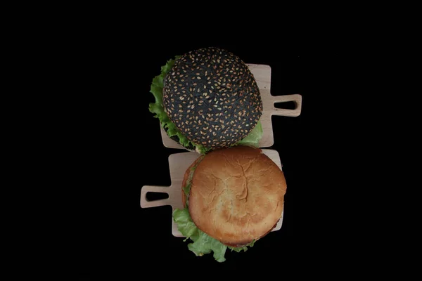Zwei Hamburger Auf Hölzernen Schneideplatten Isoliert Auf Schwarzem Hintergrund Lagen — Stockfoto