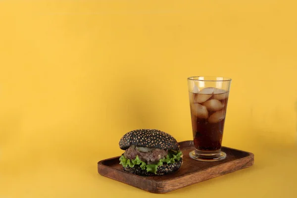 Schwarzer Hamburger Auf Holzteller Und Ein Glas Eis Isoliert Auf — Stockfoto