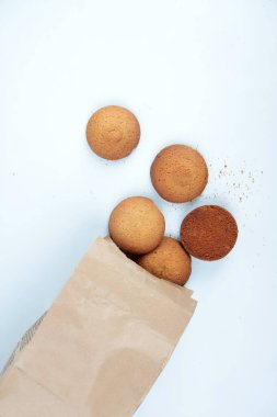 Beyaz zemin üzerinde yulaflı kurabiyeler ve kahverengi kese kağıdı vardı. Resim kopyalama alanı içeriyor