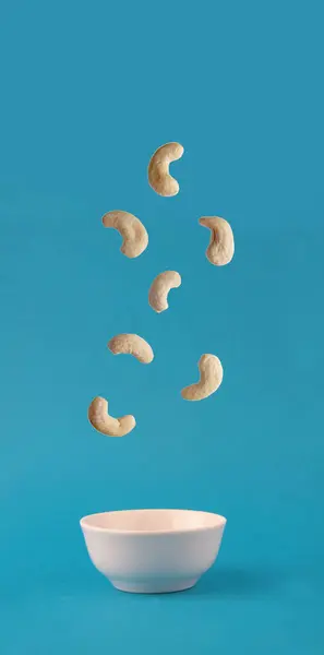 Anacardo Vertiendo Tazón Blanco Sobre Fondo Azul Concepto Comida Voladora —  Fotos de Stock