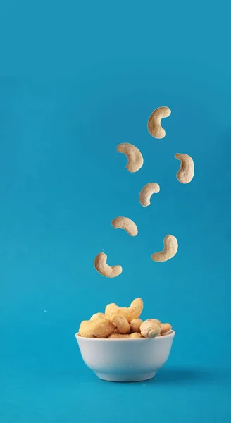 Cashew Weiße Schüssel Vor Blauem Hintergrund Gießen Konzept Des Fliegenden — Stockfoto