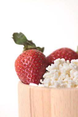 Beyaz arka planda izole edilmiş, ahşap bir peynir kasesindeki çilekler. Sağlıklı beslenme konsepti. Resim kopyalama alanı içeriyor