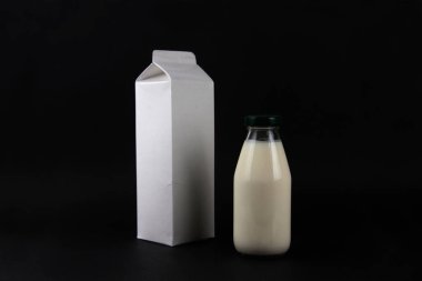 a bottle and cardboard pack of kephir isolated on black background. Fermented food concept. Image contains copy space
