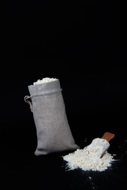 Fırın kavramı - siyah arka planda izole edilmiş bir torba ve un. Resim kopyalama alanı içeriyor