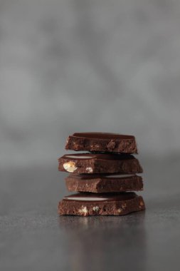 Gri arka planda izole edilmiş çikolata parçaları yığını. Çok yakından.
