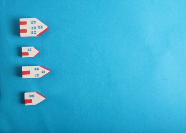 Mavi arka plandaki küçük evler mavi arkaplanda izole edilmiş. Resimler kopyalama alanı içerir. Kış arkaplanı