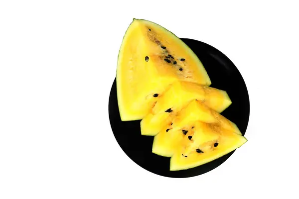 白い背景の平らな層に隔離された黒いプレートの上に黄色のスイカをカット 健康的な食事のコンセプト — ストック写真