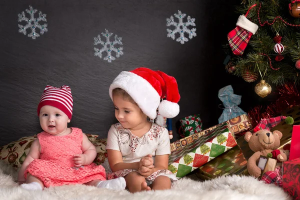 Niedliche Baby-Mädchen sitzen auf Teppich mit einem Weihnachtsgeschenk — Stockfoto