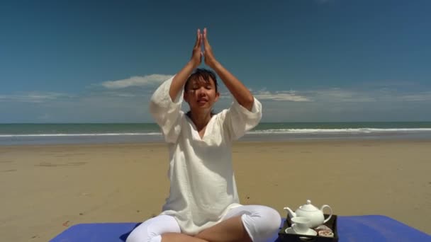 ウェルネスとリラクゼーションのコンセプト 健康的で美しいアジアの女性は 運動マットの上に座って手を上げ 熱帯ビーチで瞑想のためのヨガのハスのポーズを練習します — ストック動画