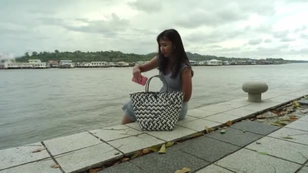 Menina Asiática Bonita Sentada Costa Rio Tirando Telefone Celular Bolsa — Vídeo de Stock