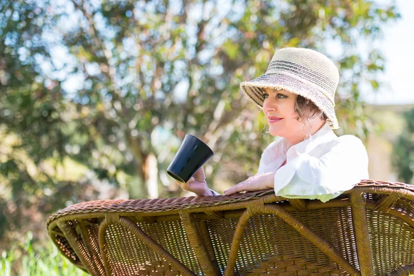 Woman  with cup of coffee  in the garden — Stock Photo, Image