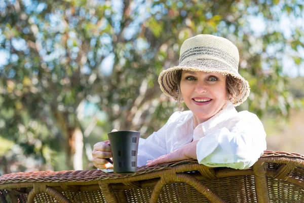 Smiling woman  with cup of coffee in the garden — Stock Photo, Image